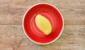 Pale yellow mango on a red plate on a wooden tabletop Royalty Free Stock Photo