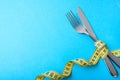 Paleo diet for weight loss. The fork and knife are wrapped in yellow measuring tape on blue