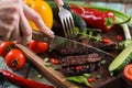 Paleo diet. Woman hands cutting well done steak on oak board served with vegetables Royalty Free Stock Photo