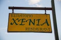 Paleokastritsa, Cofru, Greece- MAY 10, 2018Restaurant wooden hanging sing post. Yellow board with black letters chained to a brown
