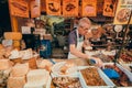 Elderly seller trading organic food, sun-dried tomatoes, olives, peppers, cheese Parmesan at local market