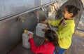 Palestinian children fetch water in jerrycans from a public fountain