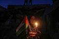 Palestinian children hold candles near buildings destroyed in Israeli air strikes