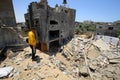 Palestinians inspect their destroyed houses by recent Israeli air strikes in the Gaza Strip