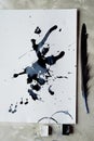 A palette of black and white paint. a sheet of white art paper with black dye ink.Old pen