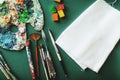 Palette with colors paints, brushes and the canvas on a green background. Painter workplace Royalty Free Stock Photo