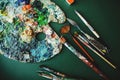 Palette with colors, paints and brushes on a green background. Painter workplace Royalty Free Stock Photo