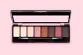 Palette of eyeshadows in brown tones, matte and shimmer eyeshadows on a pink background