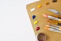 Palette with paints and brushes for oil painting on a white background