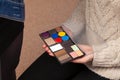 A palette of shadows with different colors of the product in the hands of a model in a beauty studio, with which makeup is applied Royalty Free Stock Photo