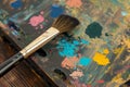 palette with vivid gouache spots and a bristle brush resting