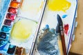 Palette with watercolors in different colors. Various brushes and pencils for drawing prepared by the artist for work. Royalty Free Stock Photo