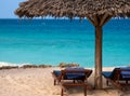 Palm beach umbrella and two empty trestle-beds on the Turquoise ocean sandy beach under blue sky on Zanzibar. Summer Royalty Free Stock Photo