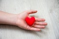 In palm of hand lying on wooden floor, is anatomical model of heart. Concept photo depicting heart or cardivascular illness such a