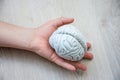 In palm of hand lying on wooden floor, is anatomical model of human brain. Concept photo depicting brain and nervous illness such