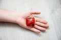 In palm of hand lying on wooden floor, is anatomical model of thyroid gland. Concept photo depicting thyroid illness such as cance