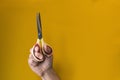 Palm holding vertically up scissors with yellow handles on yellow background. Royalty Free Stock Photo
