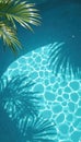 Palm leaf shadows fall on clear blue swimming pool water surface. Sunlit azure water sparkles with light reflections on bright Royalty Free Stock Photo