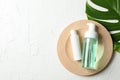 Palm leaf, wood plate, bottles with scrub and cream on white background