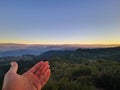 Palm of a man against a forest landscape during sunset Royalty Free Stock Photo