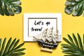 Palm and monstera leaves, orchid, seashells, white photo frame, ship on a yellow background.