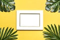 Palm and monstera leaves, orchid, seashells, white photo frame, ship on a yellow background.
