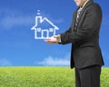 Palm opening businessman with cloud shape house in green meadow Royalty Free Stock Photo