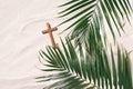 Palm Sunday concept. Cross made of palm and tropical leaves on sand background. Christian moveable feast to celebrate Royalty Free Stock Photo