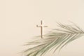 Palm Sunday and Easter concept. Cross or crucifix and palm leaf on light beige background Royalty Free Stock Photo