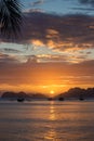 Palm tree and boats silhouettes on bright sunset sky background. Scenic sunset on tropical beach with mountains on background. Royalty Free Stock Photo