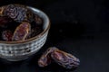 Palm tree fruit dry date on a white bowl on black wooden background, close up Royalty Free Stock Photo