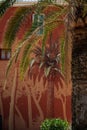 Palm tree and wall painting graffiti on a red facade. Summer scene in cote d\'azur, France