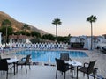 Palm trees against the background of mountains and blue sky. Tall tropical trees on a summer evening at sunset. Swimming pool of Royalty Free Stock Photo