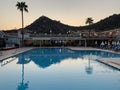 Palm trees against the background of mountains and blue sky. Tall tropical trees on a summer evening at sunset. Swimming pool of Royalty Free Stock Photo