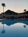 Palm trees against the background of mountains and blue sky. Tall tropical trees on a summer evening at sunset. Swimming pool of Royalty Free Stock Photo