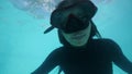 Attractive asian girl in snorkeling mask diving in pool and swimming underwater.