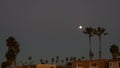 Palm trees silhouettes and full moon in twilight sky, California beach houses. Royalty Free Stock Photo