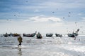 Palmarin, Senegal - October 30, 2013: Unidentified fisherman running in water to traditional painted wooden fishing boat