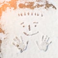 Palmprints of man and a human smiling face drawn on the snow
