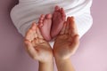 The palms of the father, the mother are holding the foot of the newborn baby in a pink background. Royalty Free Stock Photo