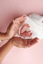 The palms of he mother are holding the foot of the newborn baby in a white blanket, pink background. Royalty Free Stock Photo
