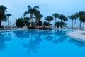 Palms reflect on calm pool water. Water mirror reflect. Swimming pool reflect hotel landscape. Reflection on the water