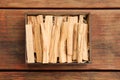 Palo Santo sticks in box on wooden table, top view