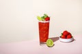 Paloma alcoholic cocktail drink with tequila, grapefruit and lime juice, strawberries, mint and ice in glass with salty rim. Beige Royalty Free Stock Photo