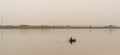 Fisherman in a small wooden boat collecting nets in a calm Odiel River near Huelva