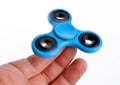 Palying with a blue Fidget Spinner. Royalty Free Stock Photo