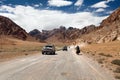 Pamir highway or pamirskij trakt with biker and two cars