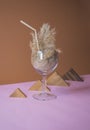 Pampas grass cocktail in a a glass with a straw made of pampas stem.