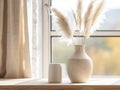 Pampas grass in decorative ceramic vase on table against blurred window and white wall with poster Royalty Free Stock Photo