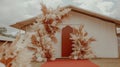 Pampas grass wedding arch, outdoor ceremony, rustic building backdrop Royalty Free Stock Photo